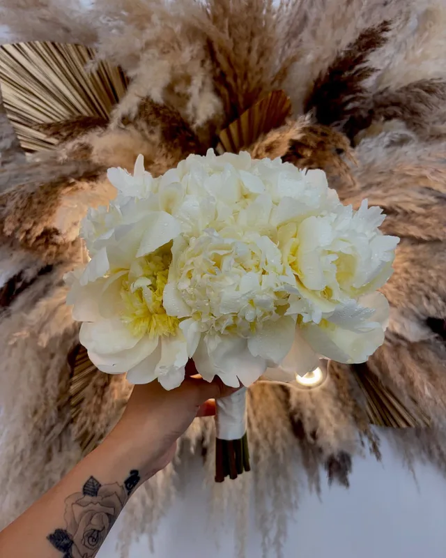 Ivory peony bridal bouquet framed by pampas grass
