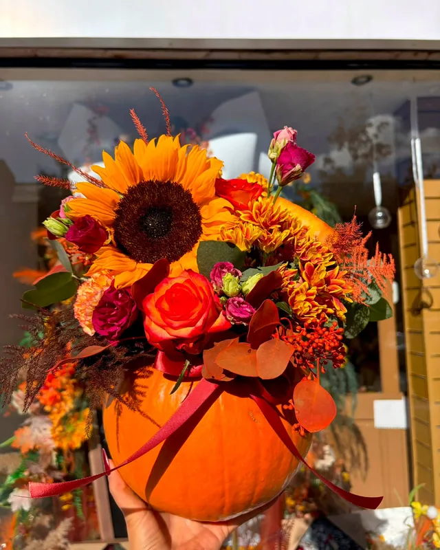 Autumn pumpkin filled with sunflowers and roses